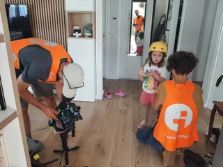 Marc filme une enfants qui se prépare à sortir à vélo. Ils sont à l'intérieur d'une maison.