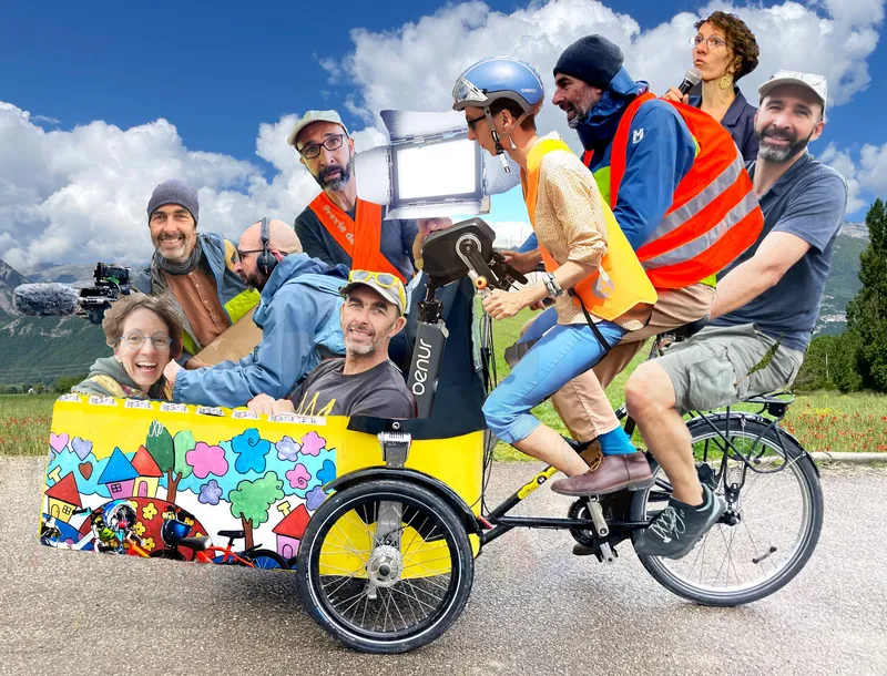 Selfie de Camille, Marc et Thomas. Les trois sourient. Ils sont habillés de gilet fluo. Il fait grand soleil. En arrière plan, on devine la Place Bellecour à Lyon.